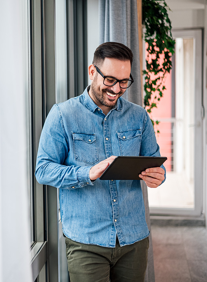 Man standing in office with tablet smiling