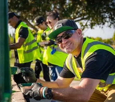 Picture of a volunteer smiling at the camera, many others in the background
