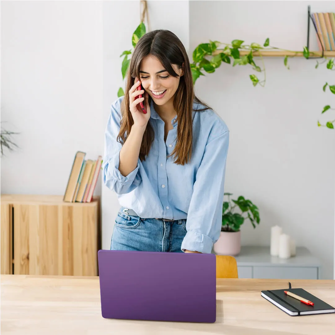 Woman talking on a phone looking at a purple laptop
